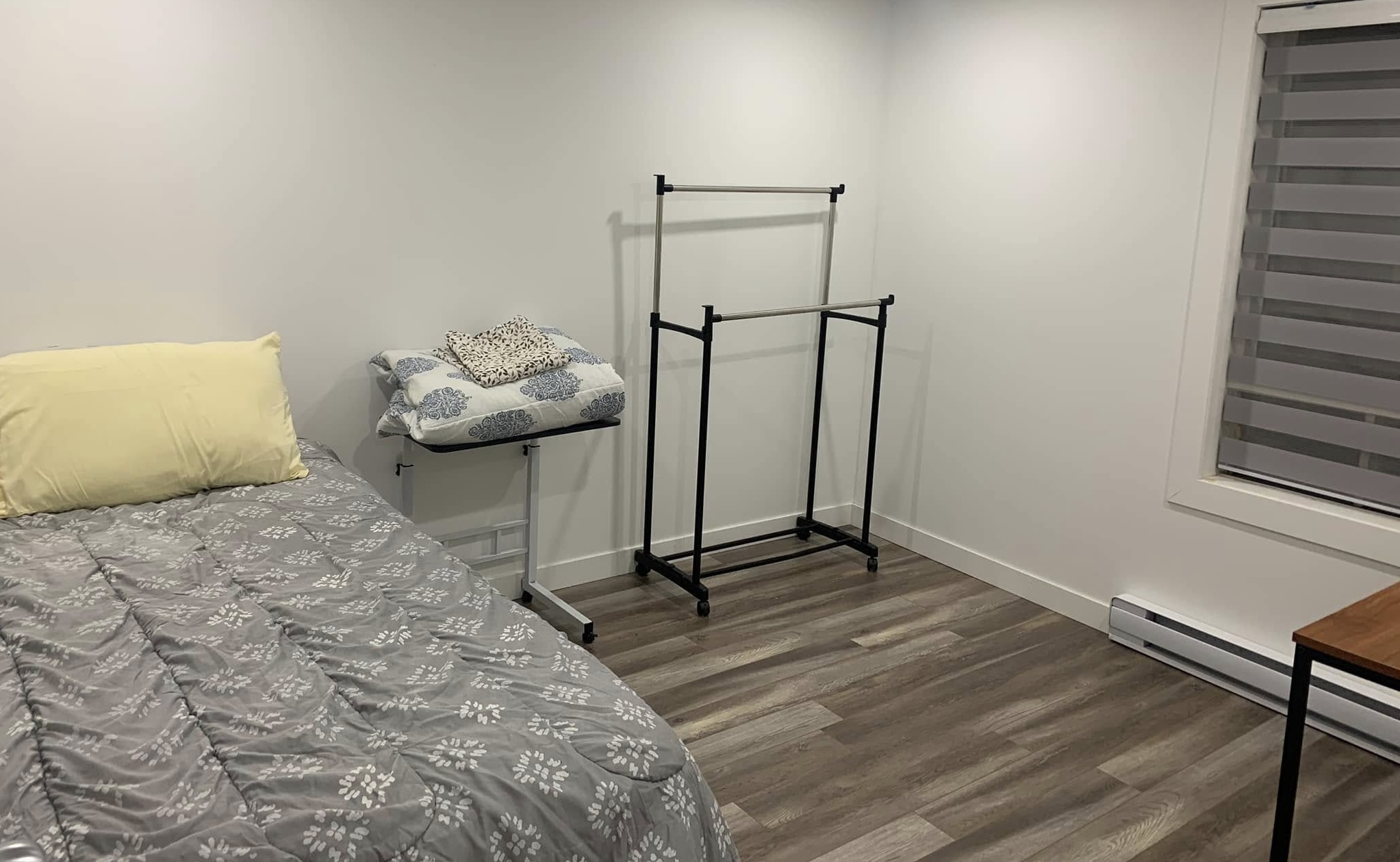 Chambre avec lit simple, table de chevet et support de rangement